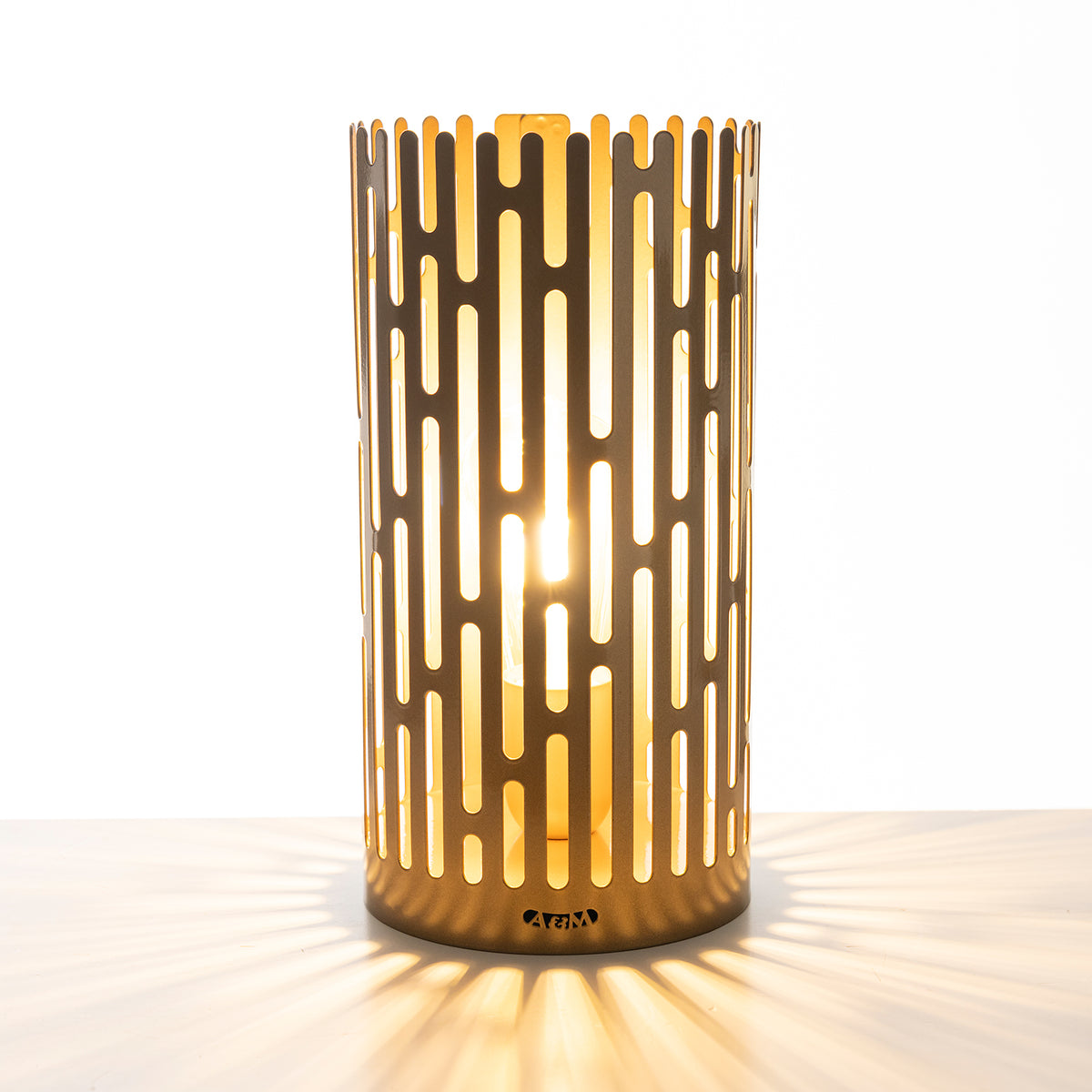 Lampada decorativa Kamalea Arti&Mestieri in oro laccato accesa con giochi di luce sul piano d'appoggio